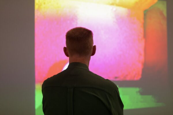 Photo of a person viewing a multi-colored digital artwork.