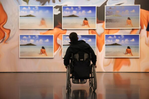 Person in a wheelchair looks on at a wall of art.
