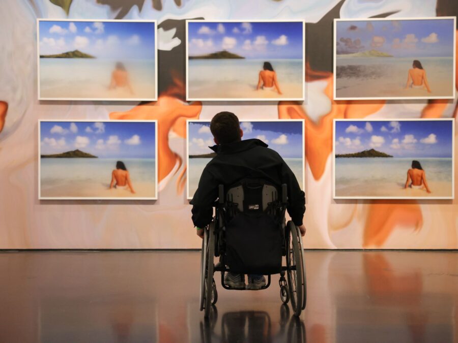 Person in a wheelchair looks on at a wall of art.