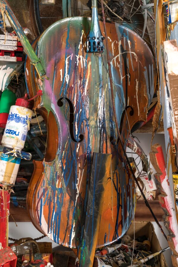 A paint covered cello is just decipherable amid a collage of art making supplies