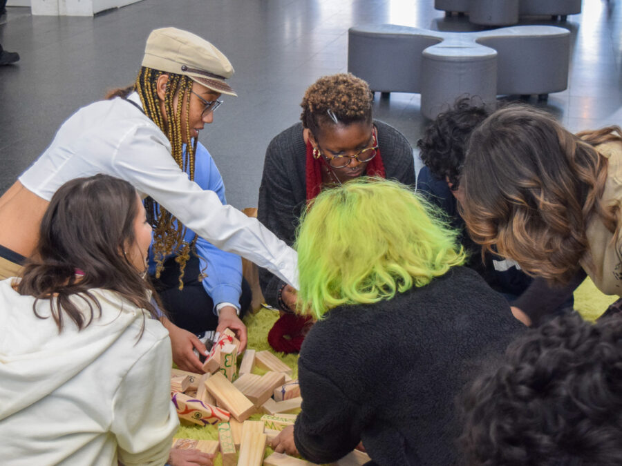 A group of people lean in together to view and discuss an object.