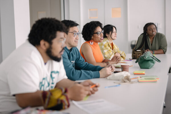 A group of people gather on one side of a table looking at something on the other side.
