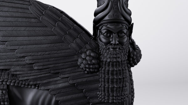 A dark sculpture of a winged deity with a long beard.