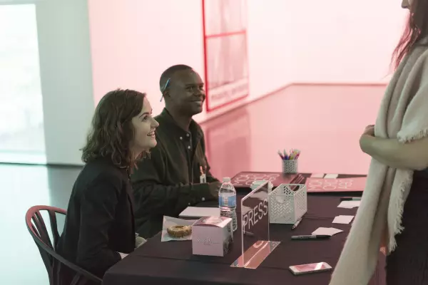Two people sitting at a black table smile up at someone mostly off camera