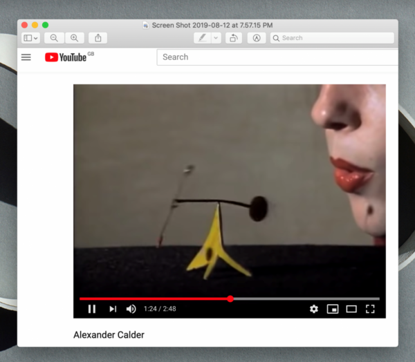 A screen capture of a YouTube video shows a small yellow mobile on a table. Above it, a person with red lips appears to blow on it.