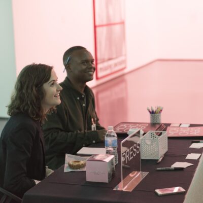 Two people sitting at a black table smile up at someone mostly off camera
