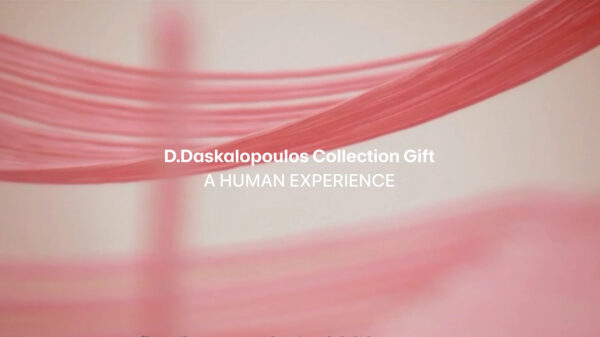 The words D Daskalopoulos Collection Gift A Human Experience appear in white over pieces of pink fabric strung up in a white room