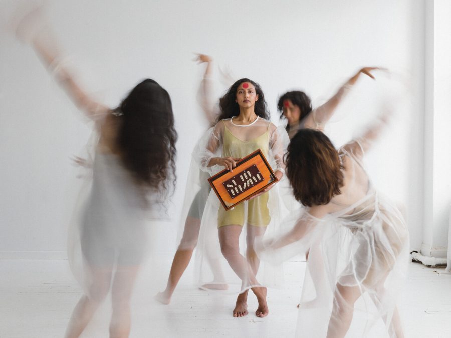 Four people in transparent dresses circle around one person in the center.