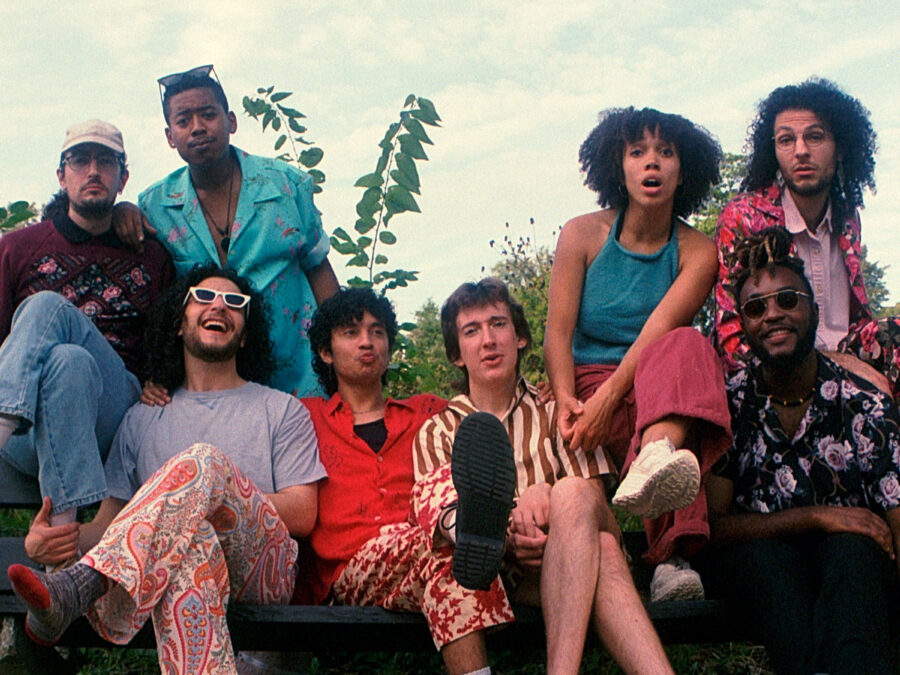 Group photo of people in 1970s clothes sitting outdoors