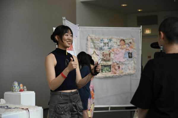 A person gives two thumbs up next to a table filled with artwork