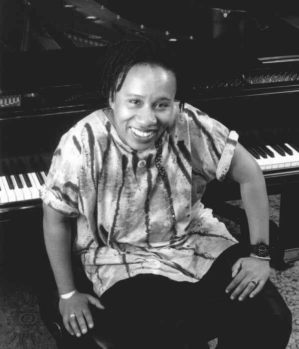 Black and white portrait of a female presenting person sitting at a piano