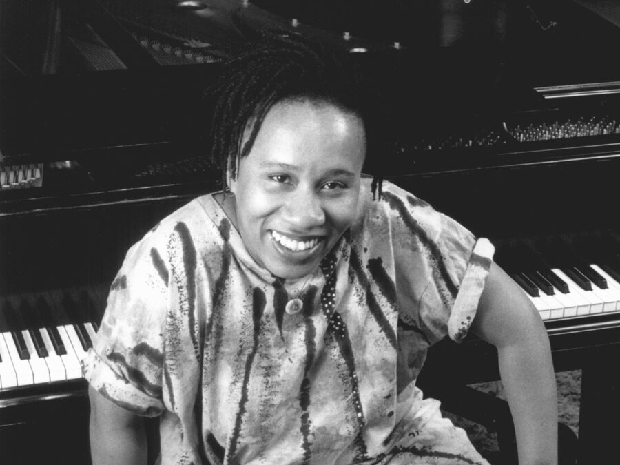 Black and white portrait of a female presenting person sitting at a piano