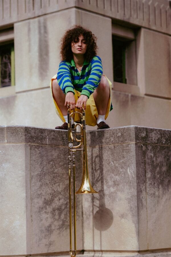 Portrait of a female presenting person holding a trombone