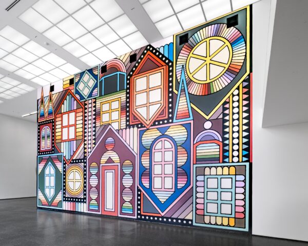 A two-story wall filled with a illustrated mural of colorful dormers, some upright, some upside down, featuring different style windows around a door in the middle.