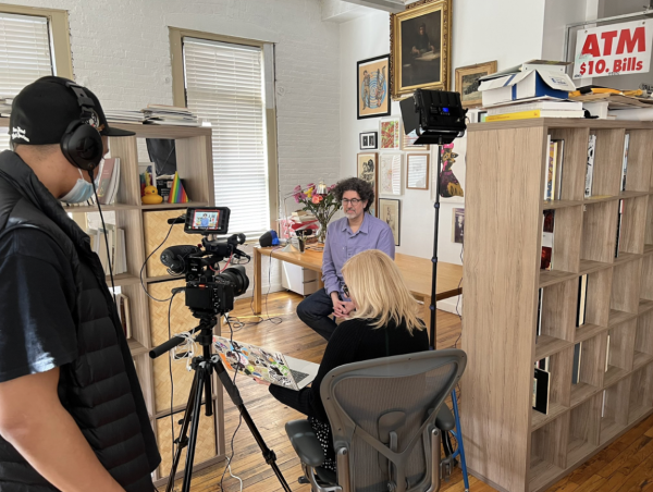 Cameras and lights surround a person sitting in a living room