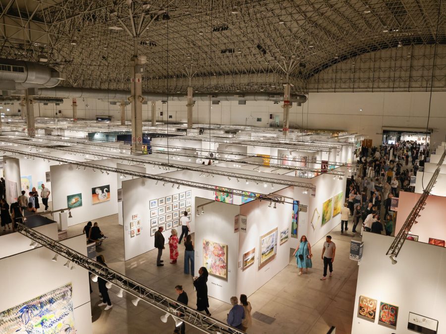 An overhead view of an art fair in a large, airy building.