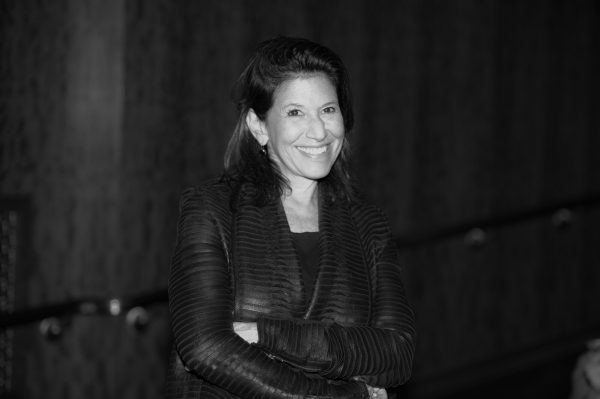 Black and white photo of a female-presenting person smiling with crossed arms