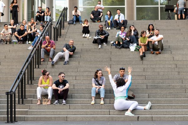 People sitting on stairs watching a person performing amongst them