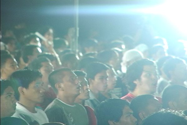 A crowd of men cast in a haze from a bright light above them