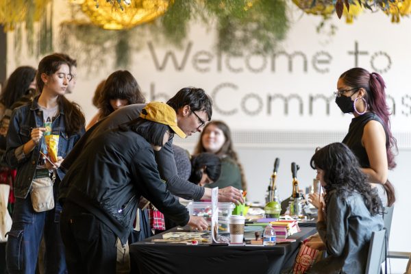 People gather around a table and look at various objects on it.