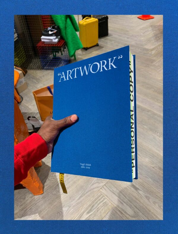 Image of a left arm holding out a blue book titled Artwork on the cover of a blue book