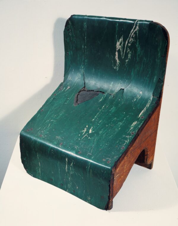 A wooden slanted stepstool covered with a green marbleized plastic coating on top, which is wearing away in one spot to reveal a black ridged grip pad.