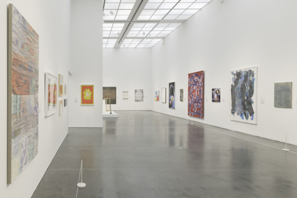 A large gallery space with several colorful artworks hanging on white walls