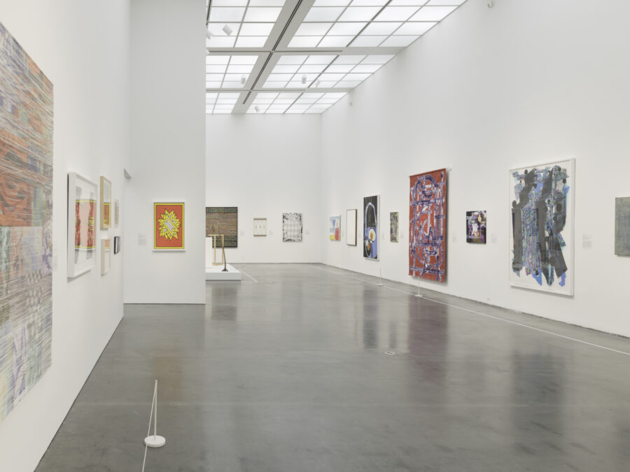 A large gallery space with several colorful artworks hanging on white walls