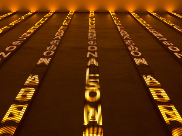 Large letters illuminated in yellow in vertical rows on the floor. These letters cast a warm glow over the room.