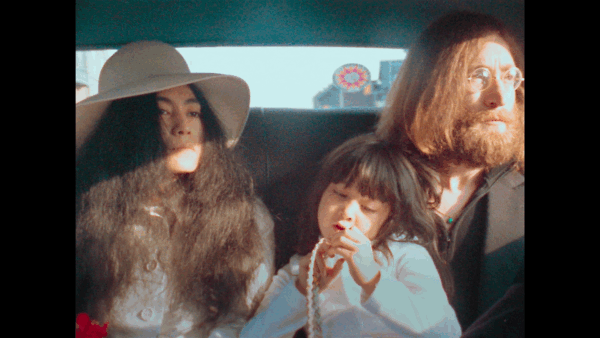 Yoko Ono, a child, and John Lennon sitting in the back seat of a car