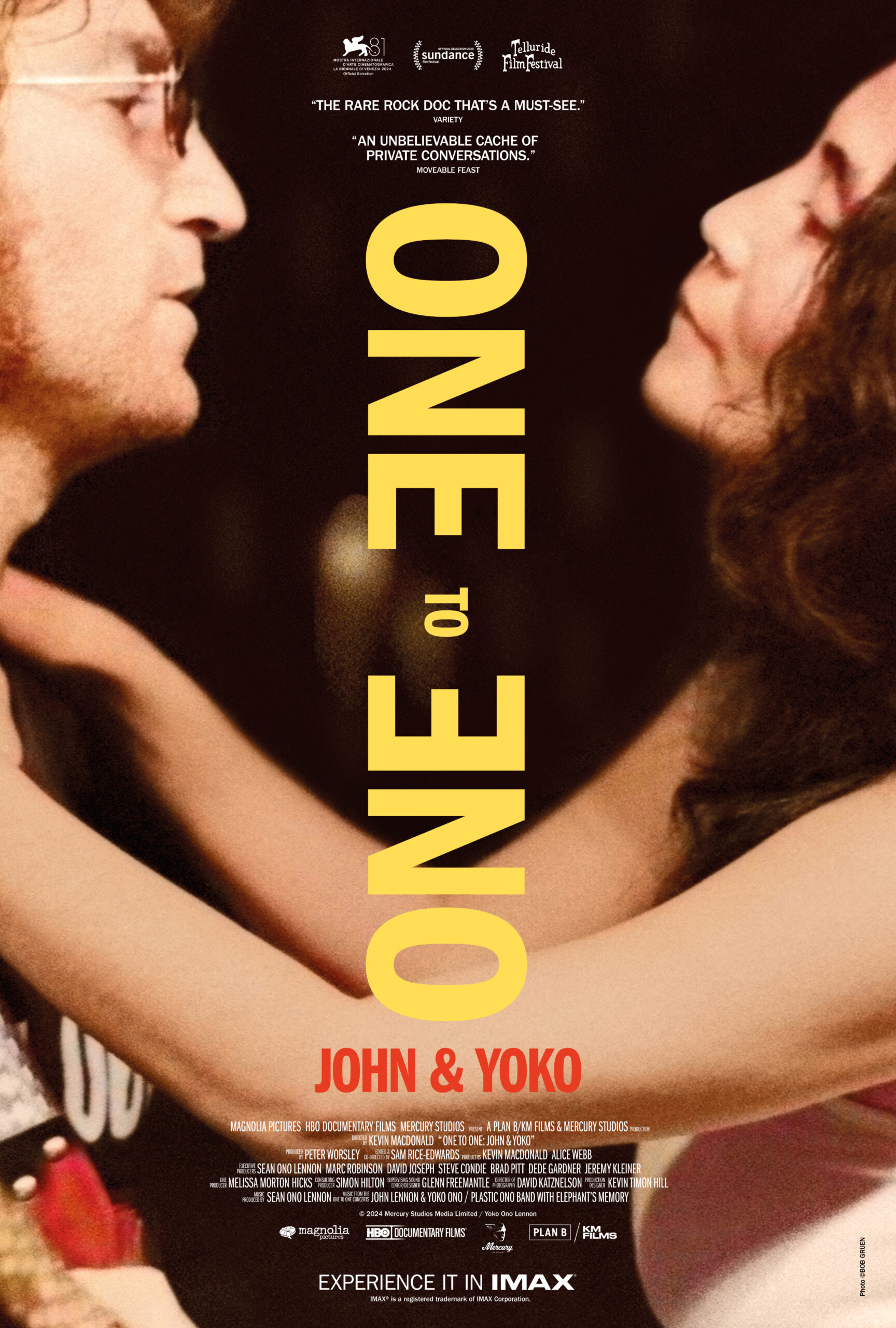 Promotional poster for One to One, John and Yoko featuring the yellow text separating Yoko Ono on the right side of the sheet as she wraps her arms around John Lennon who appears on the left side of the sheet