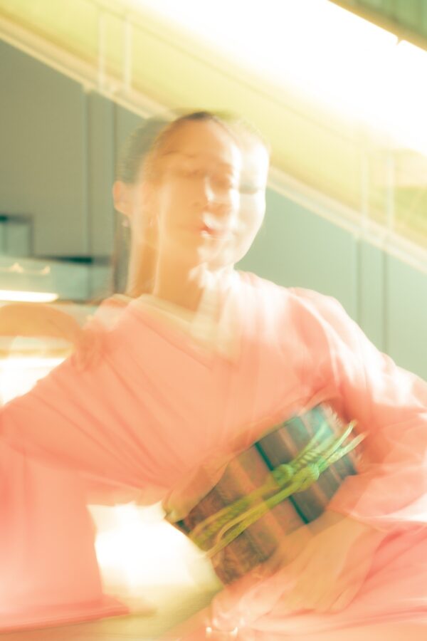 Blurry image of a person in a peach yukata and striped obi