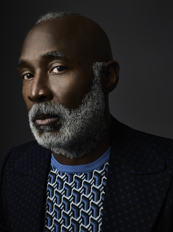 Three-quarter portrait of Nick Cave, a Black man with a tight grey beard, against a dark background