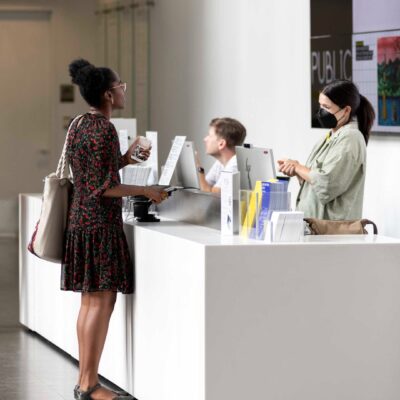 A person stands at an admission desk staffed by two people