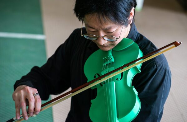 A close up of a person playing a bright green violin