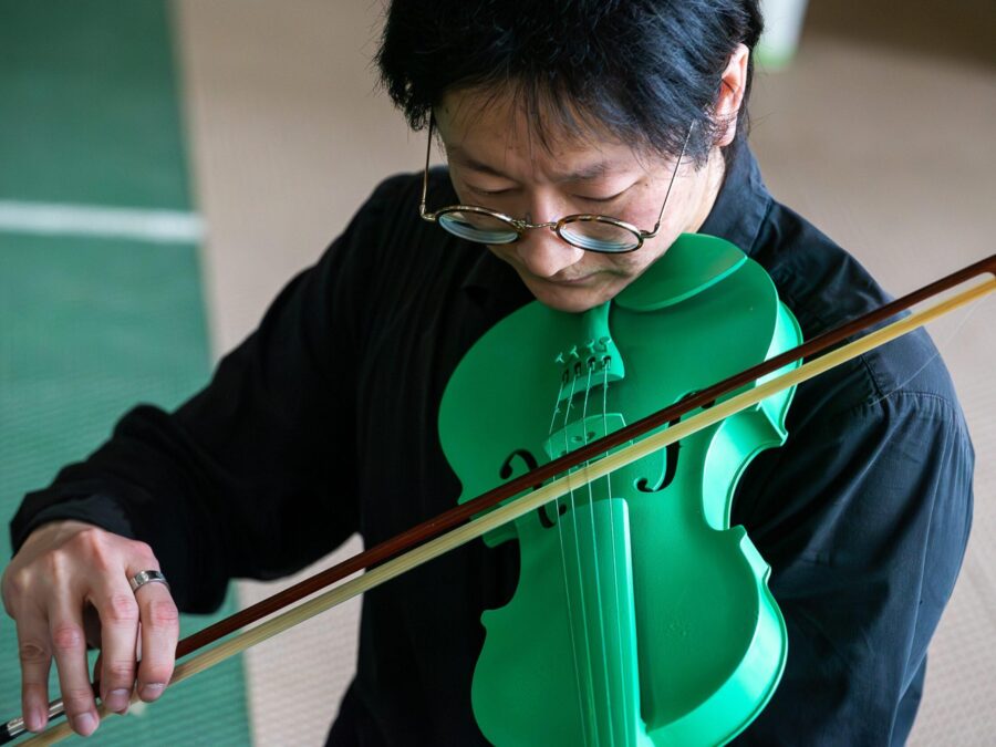 A close up of a person playing a bright green violin