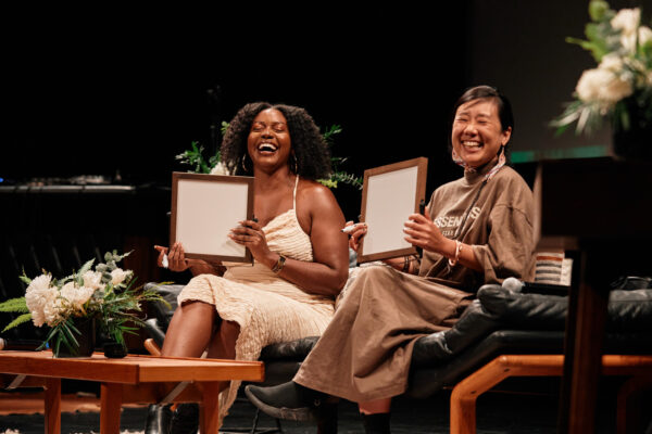 Two people laugh while sitting on a couch holding blank frames