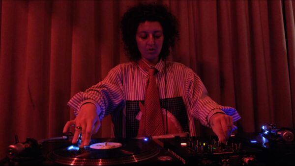 Red toned image of a person spinning records