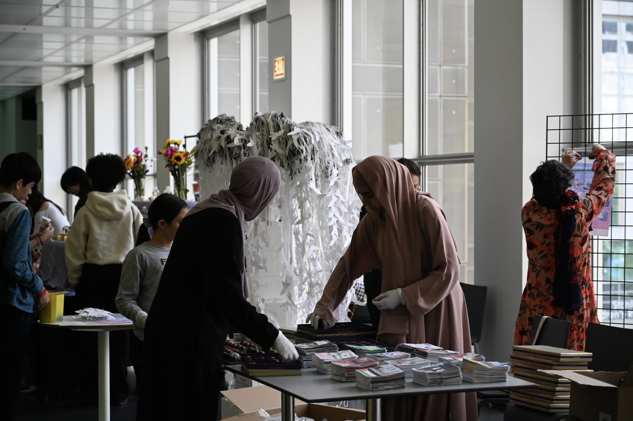 People brows zines on tables amid other artworks and tables