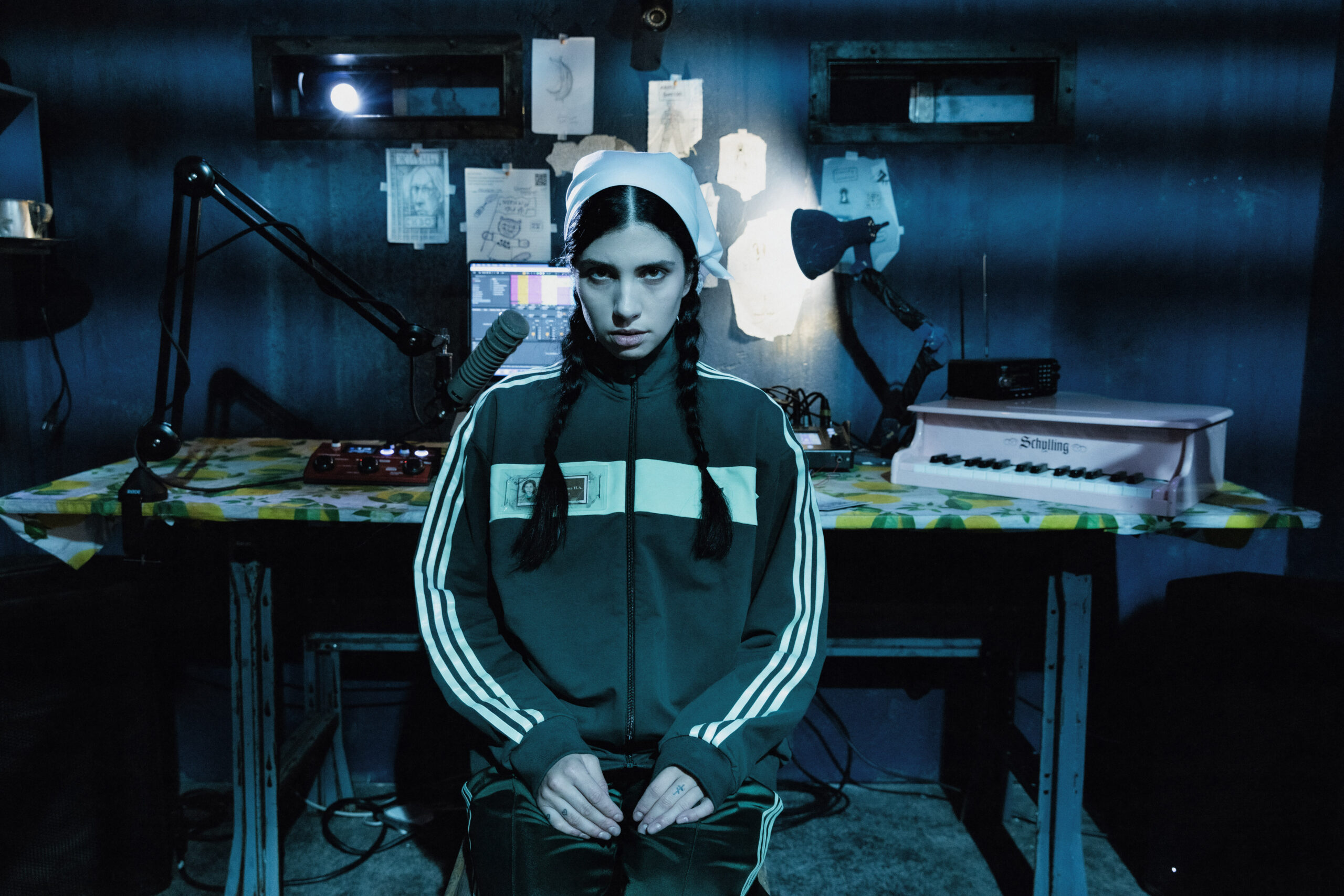A blue-cast image of a person sitting in an office-like space looking directly at the camera