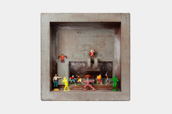 A square box displays small action figures. Inside, several colorful characters, including Spiderman, are positioned dynamically. The background is a plain, rustic surface, adding a contrasting backdrop to the vibrant figures.