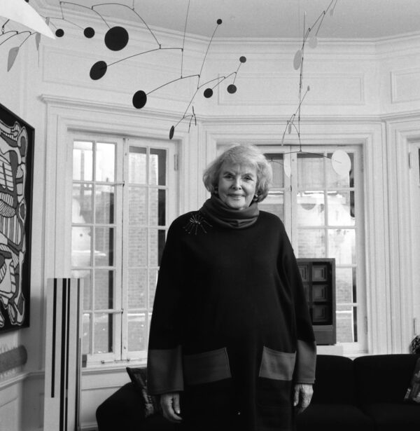 Black and white photo of a woman in a living room with an Alexander Calder mobile hanging from the ceiling