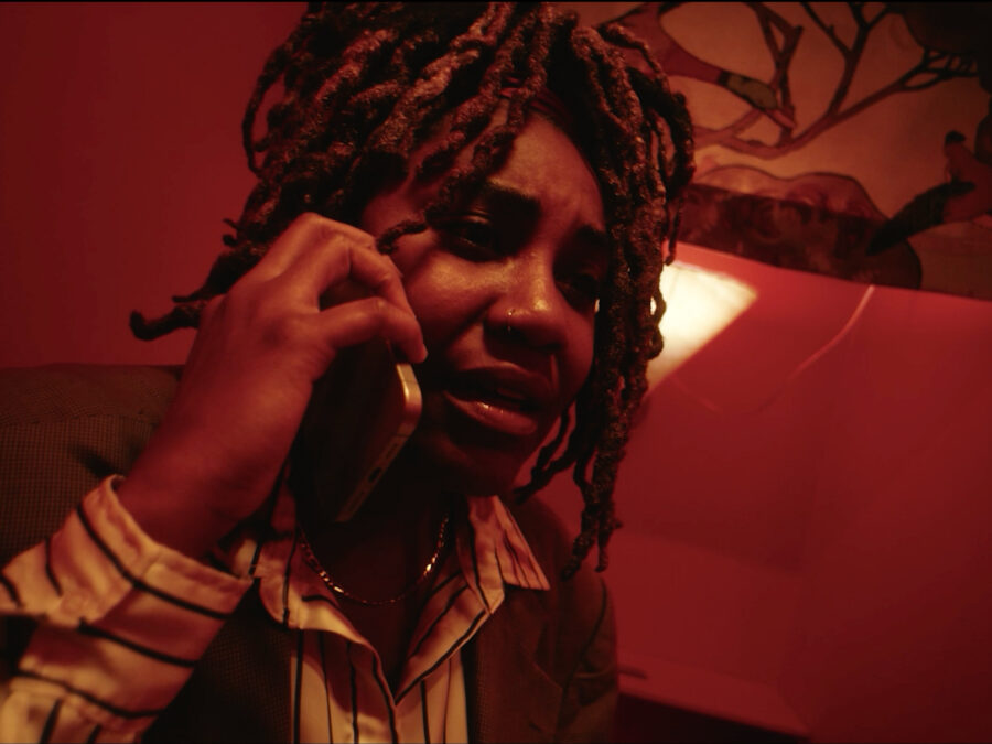 A red toned image of a person with a worried look on their face as they hold a cellphone up to their right ear