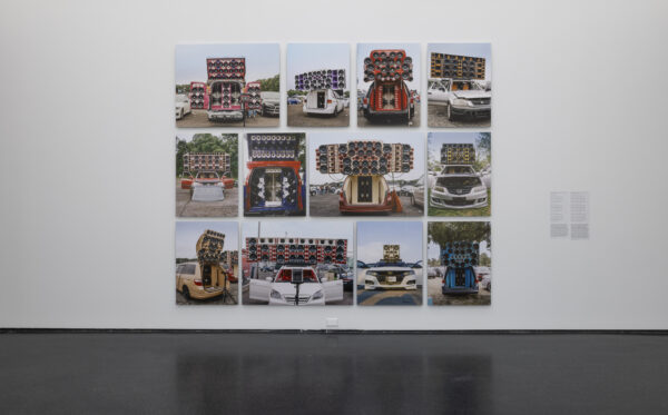 Three rows of four images on a white wall depict various cars with giant speaker systems installed in them
