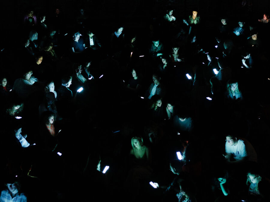 A large group of people illuminated only by the glow of their phones