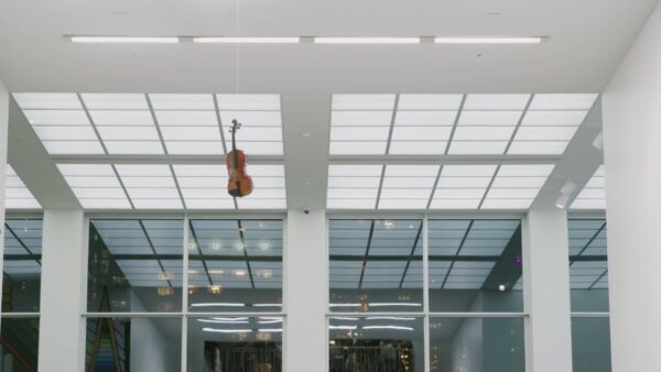A violin seemingly floating in the air near the ceiling of a tall atrium
