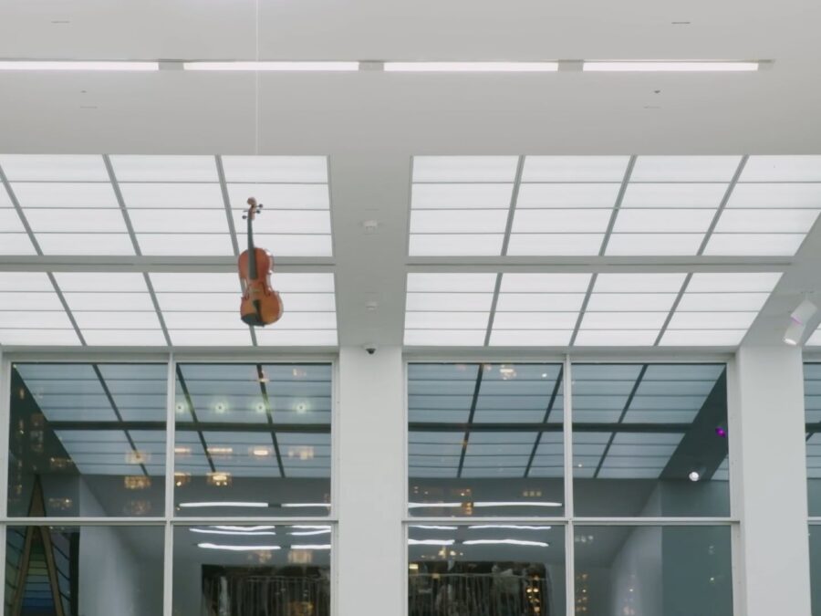 A violin seemingly floating in the air near the ceiling of a tall atrium