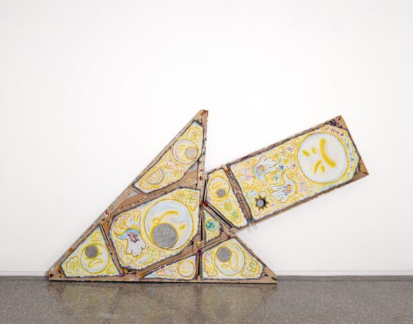 Painted emojis against a yellow background on unusually shaped canvases that form an arrow resting on the floor against a white wall