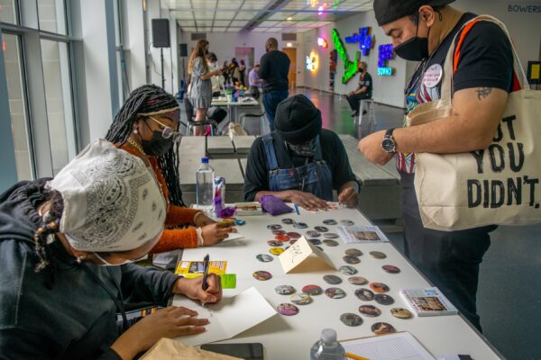 A group of people write at a tables filled with pins