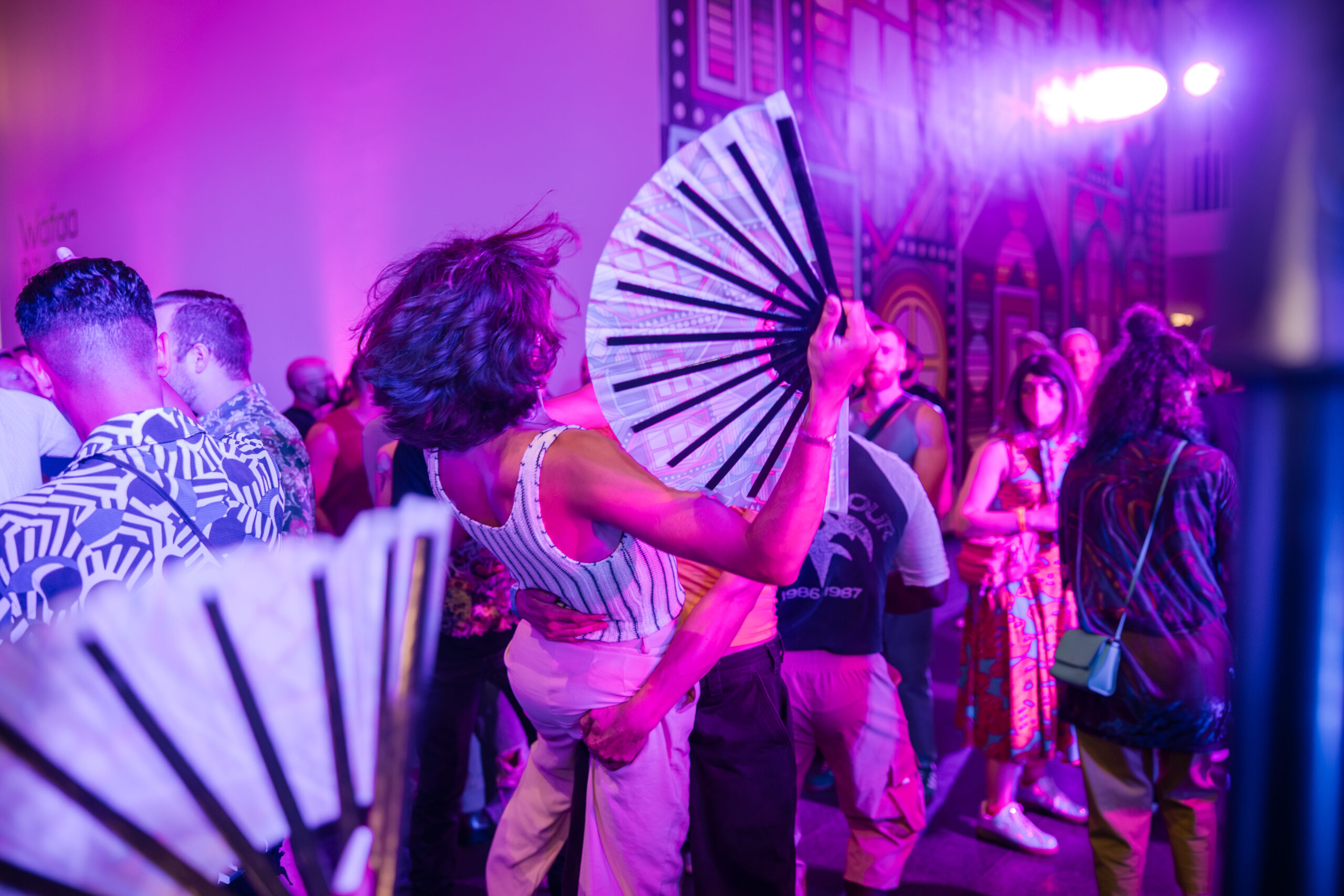 People dancing with fans in a purple lit room